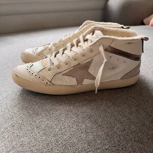 Golden goose mid star sneakers with gold stripe.